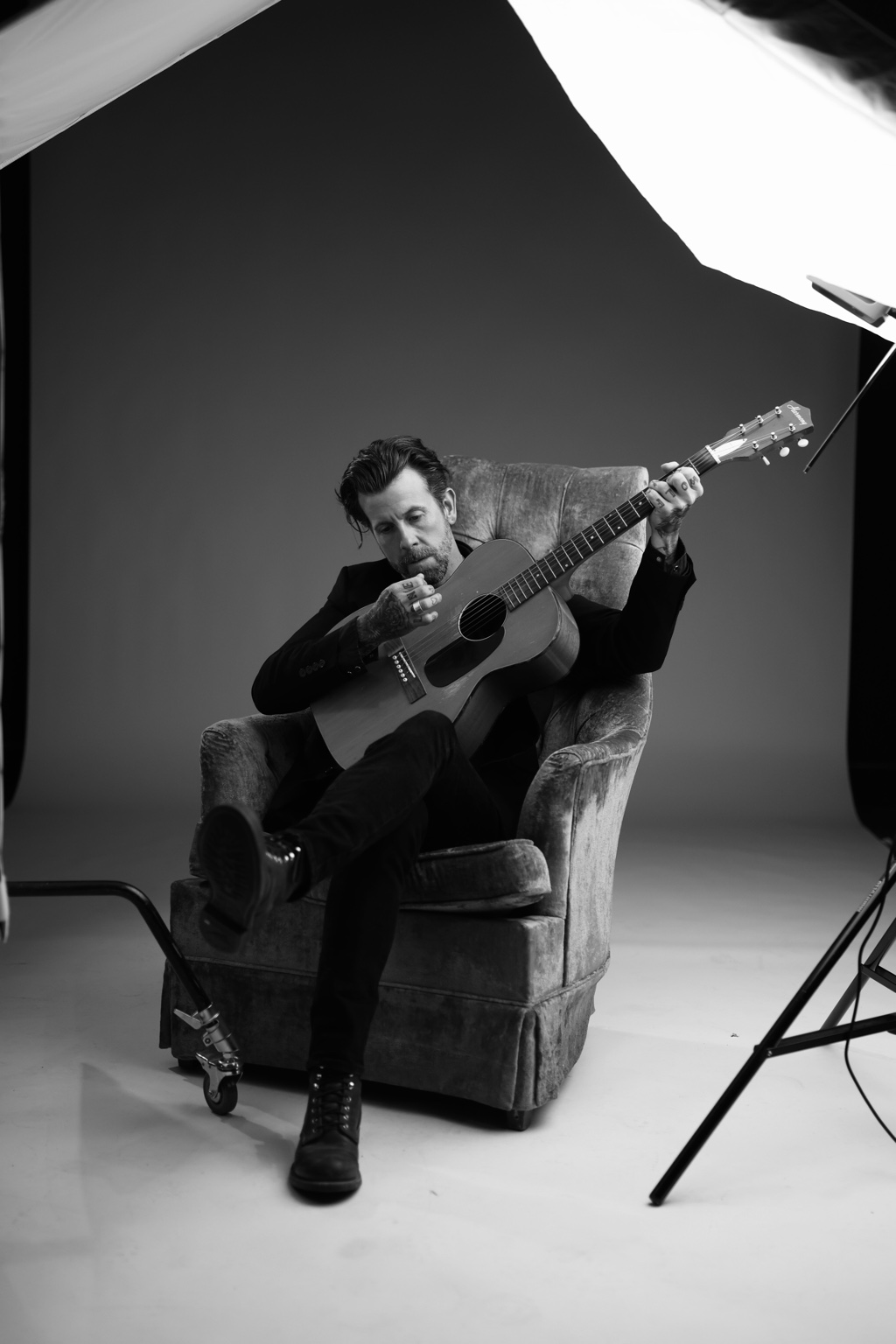 Jeremy Stanfill seated with an acoustic guitar in a studio